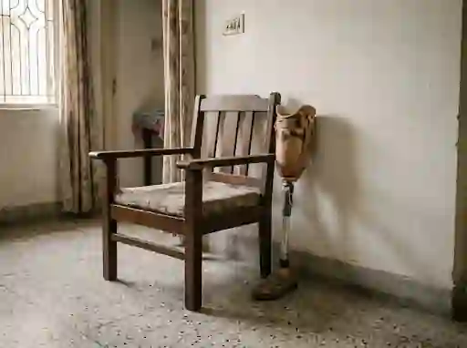 Sturdy chair with armrests beside a prosthetic leg