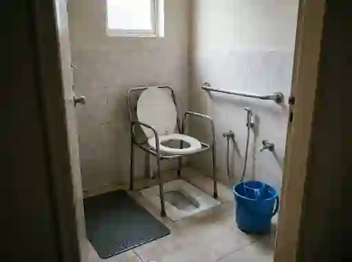 Commode chair over a squatting pan with a grab rail